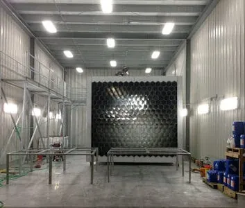 Interior of a stainless steel spray pickling and passivation bay featuring stainless steel fabrication equipment and organized workspaces, showcasing a hexagonal metal structure and bright overhead lighting for custom precision metal fabrication projects.