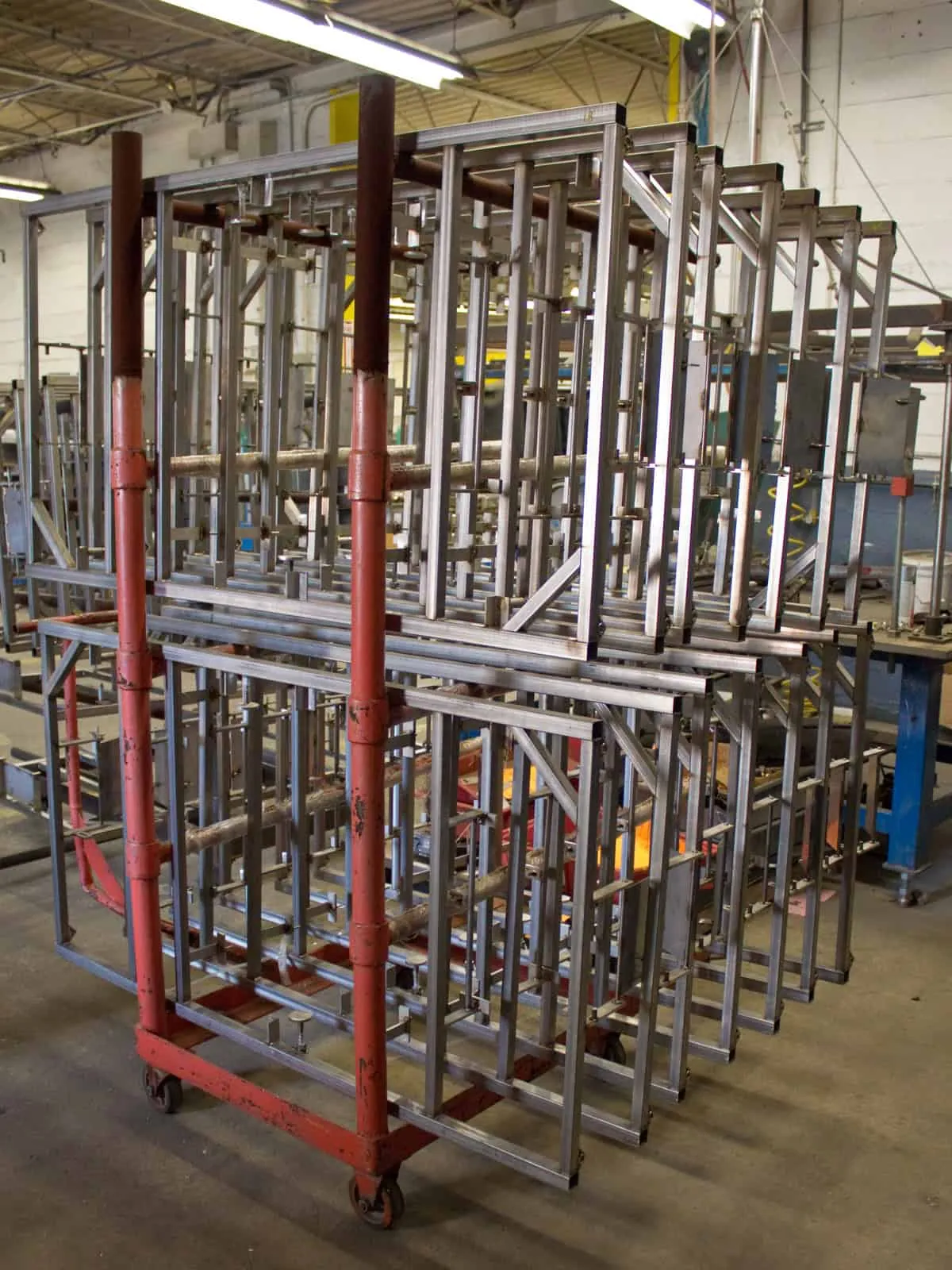 Stack of laser-cut stainless steel frame assemblies staged on a shop cart after cutting and fit-up