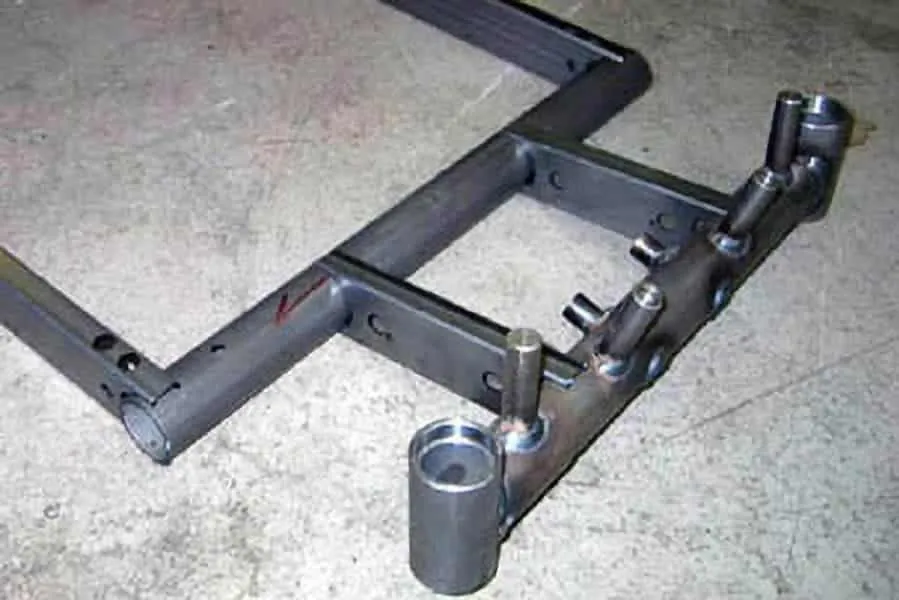 Laser-cut stainless steel tube frame with coped joints and machined bosses tack-fitted on the bench