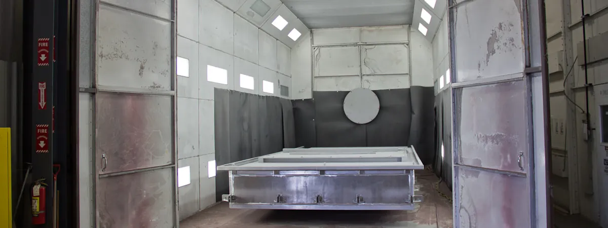 Interior of the Northern Manufacturing bead blast booth with a large palletized stainless fabrication staged for blasting