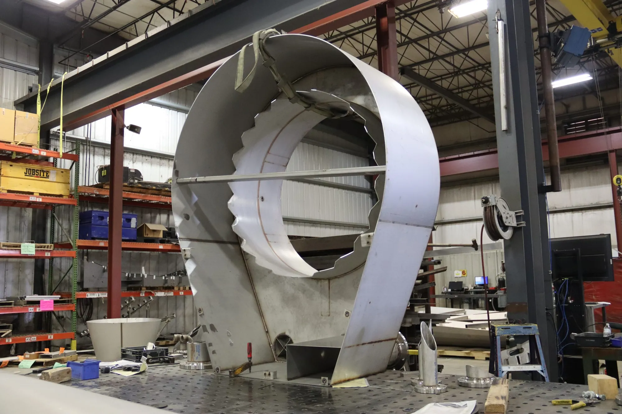 Large stainless steel scroll housing under construction on a welding fixture table