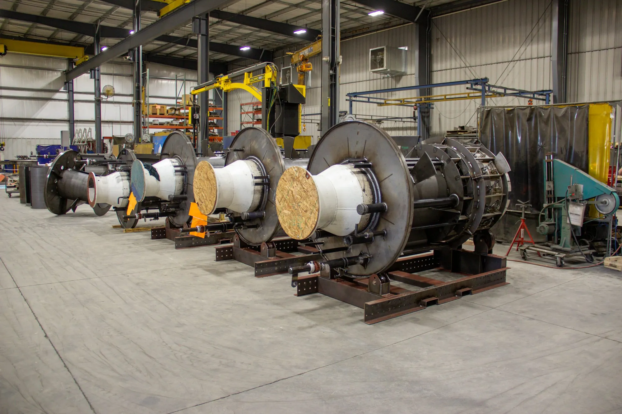Row of large refractory-lined cylindrical assemblies on steel cradles in the Northern Manufacturing fabrication bay