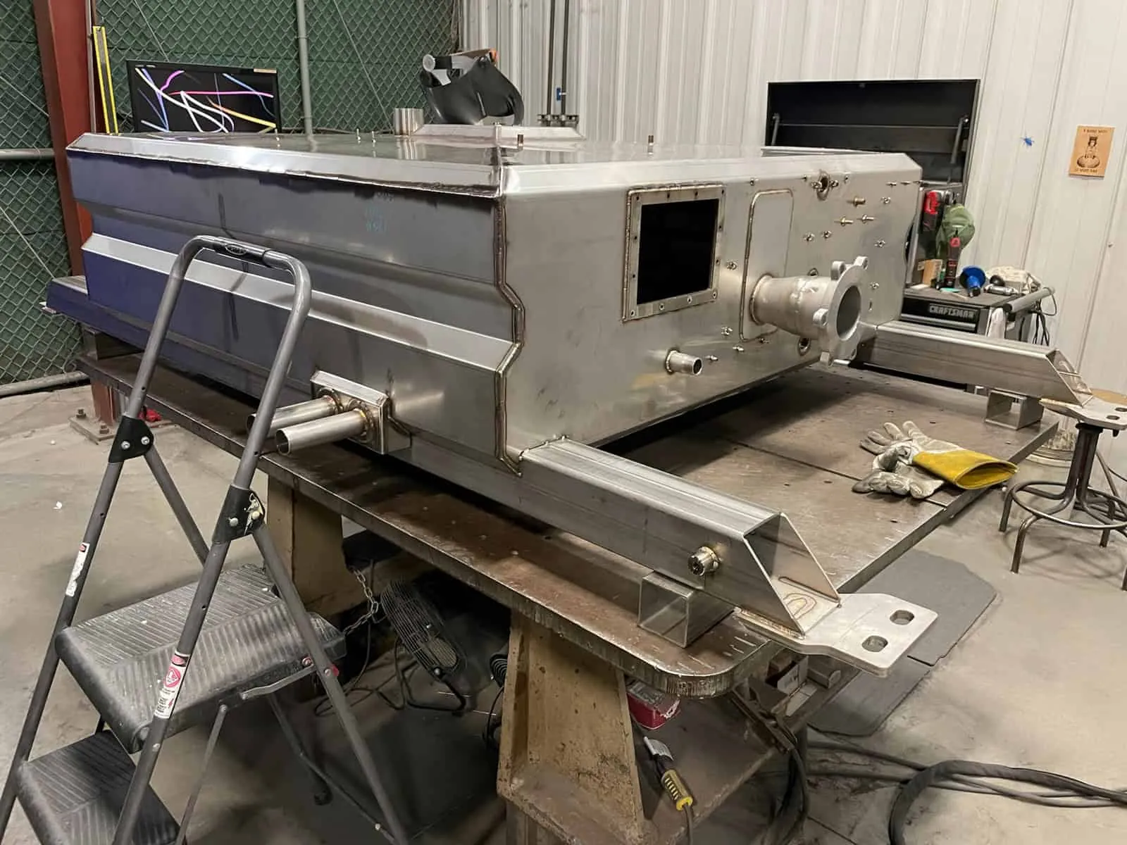 Fabricated stainless steel tank section with welded fittings and ports on a weld table at Northern Manufacturing