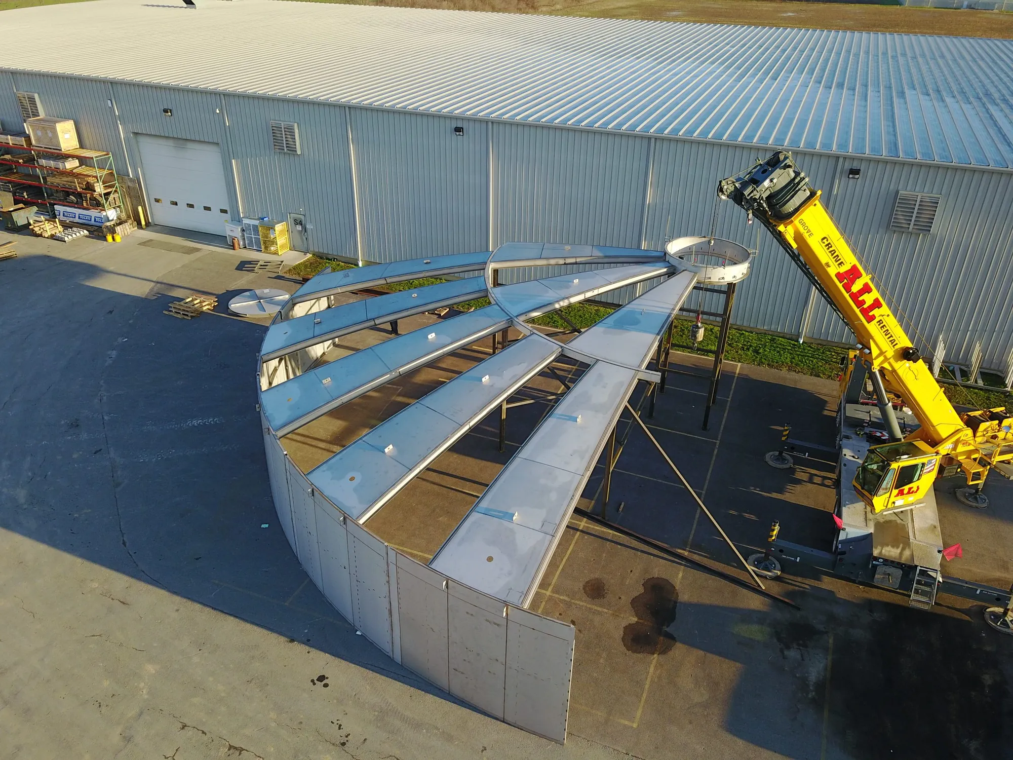 Aerial view of a large stainless steel clarifier section assembly staged outside the Northern Manufacturing shop with a crane