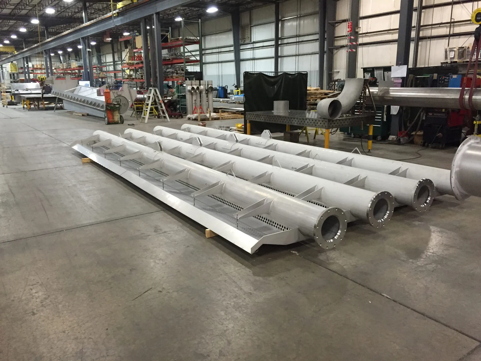 Stainless steel multi-pipe header assemblies staged on the shop floor