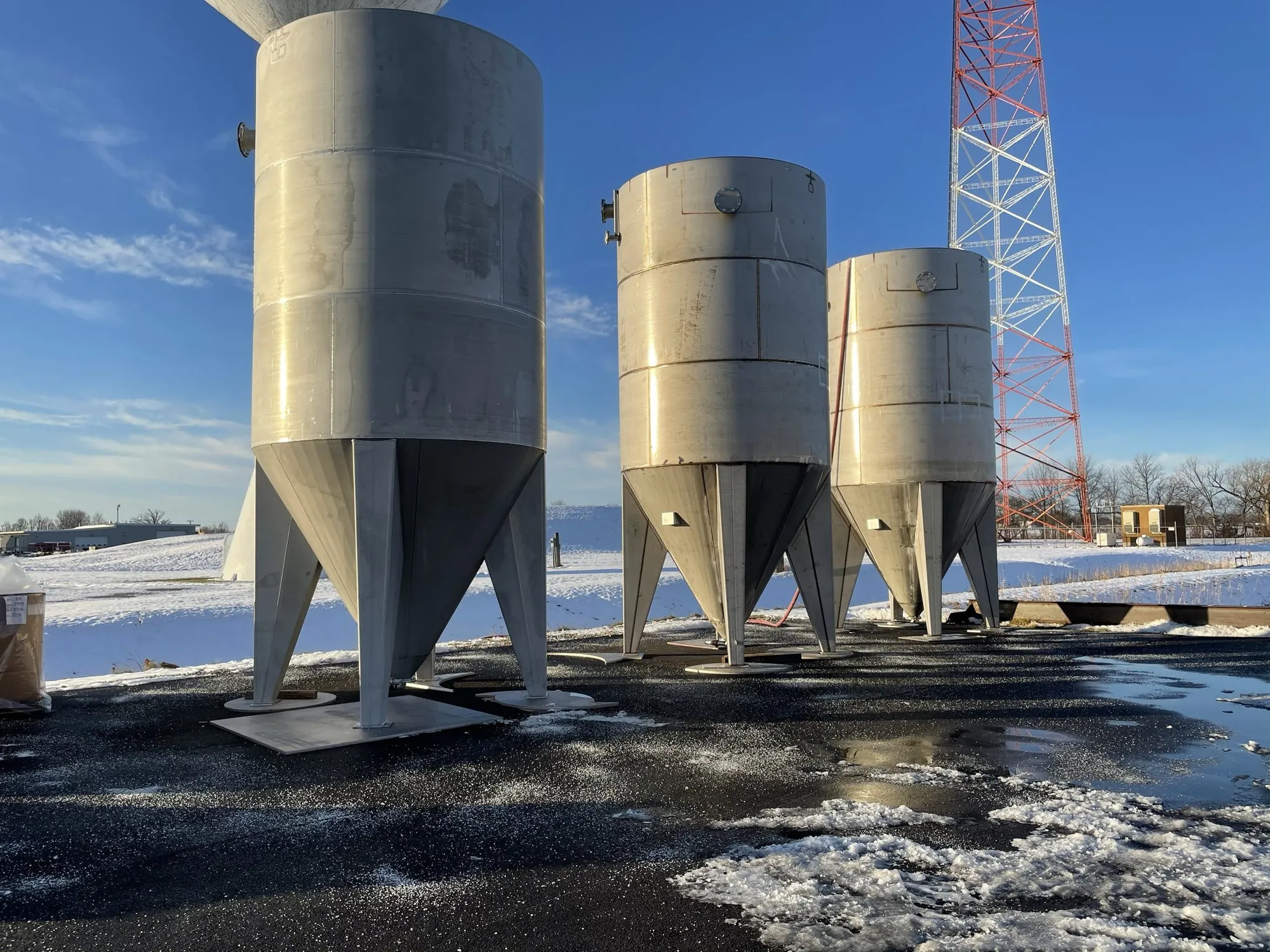 Stainless steel conical-bottom storage tanks staged outdoors