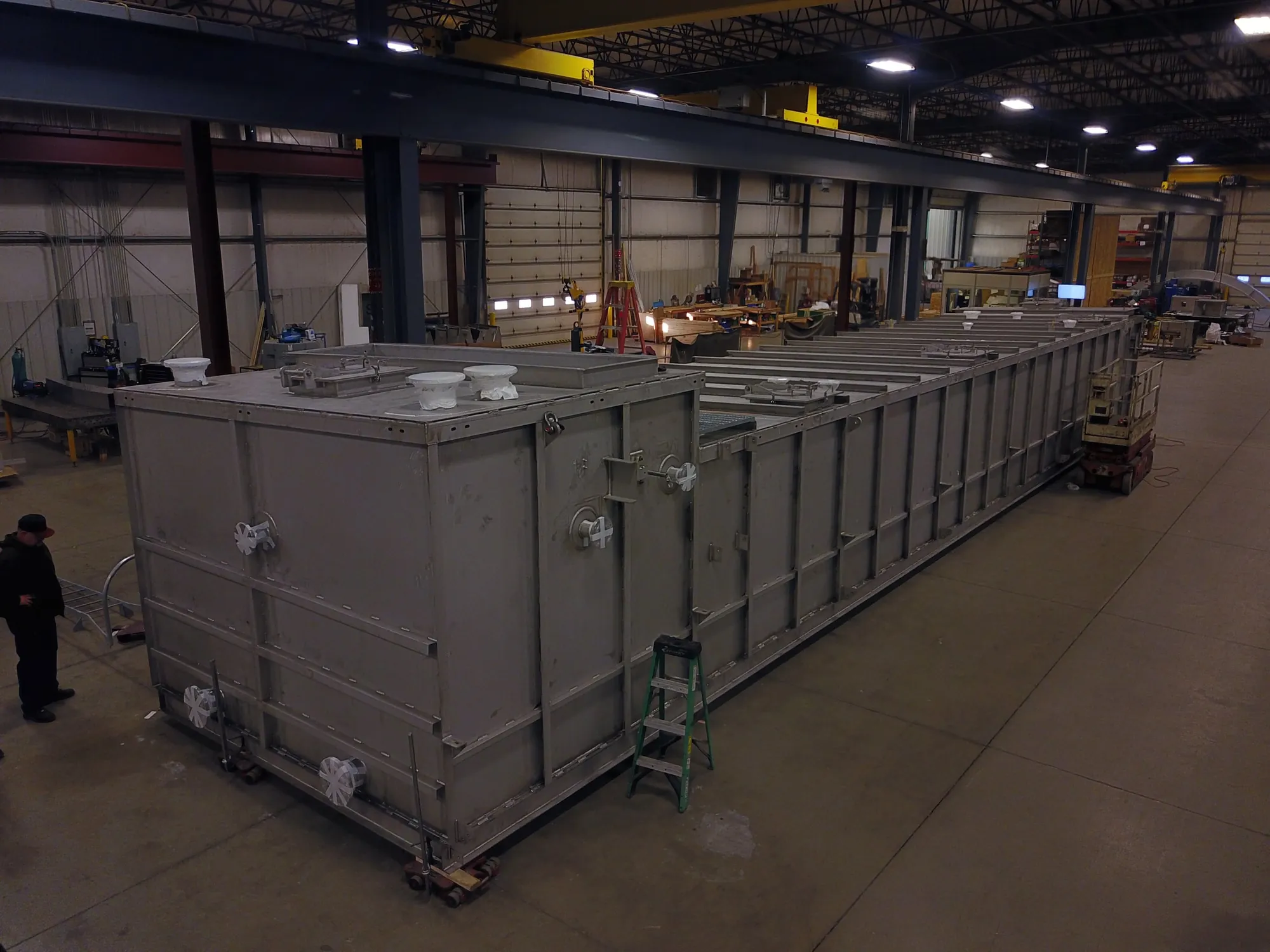 Large stainless steel wastewater tank on the Northern Manufacturing shop floor, with a fabricator alongside for scale