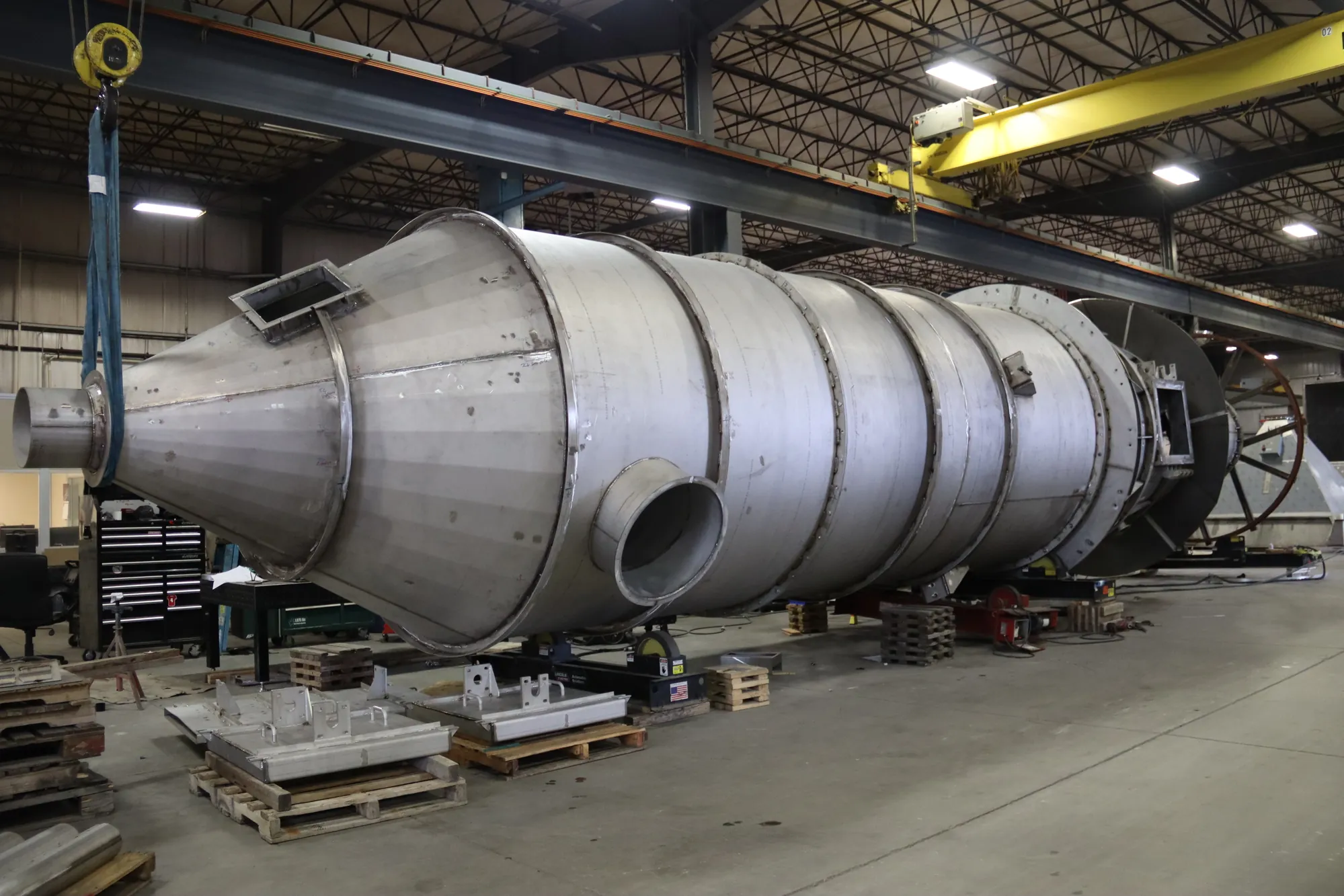 Massive lobed stainless steel power generation ductwork vessel with a conical end suspended in the Northern Manufacturing fabrication bay