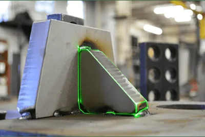 Green laser outline projected from CAD onto a stainless steel component to guide fit-up placement
