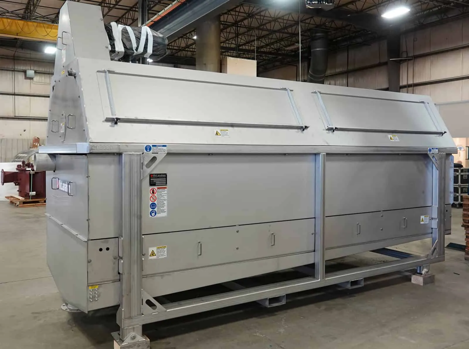 Large polished stainless steel fabrication staged in the shop with overhead machinery