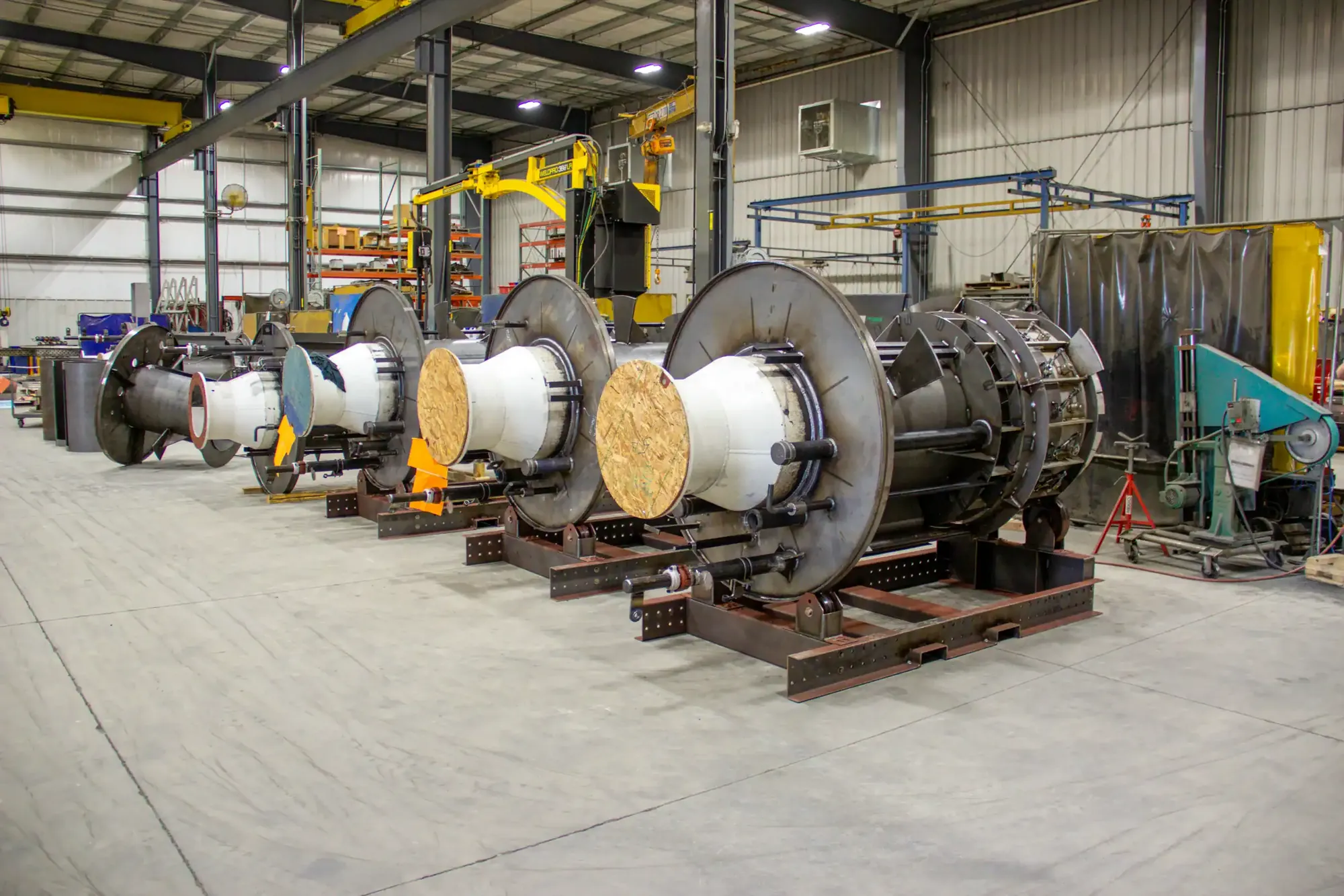 Row of large fabricated drum assemblies with wrapped cores staged on steel skids on the Northern Manufacturing shop floor