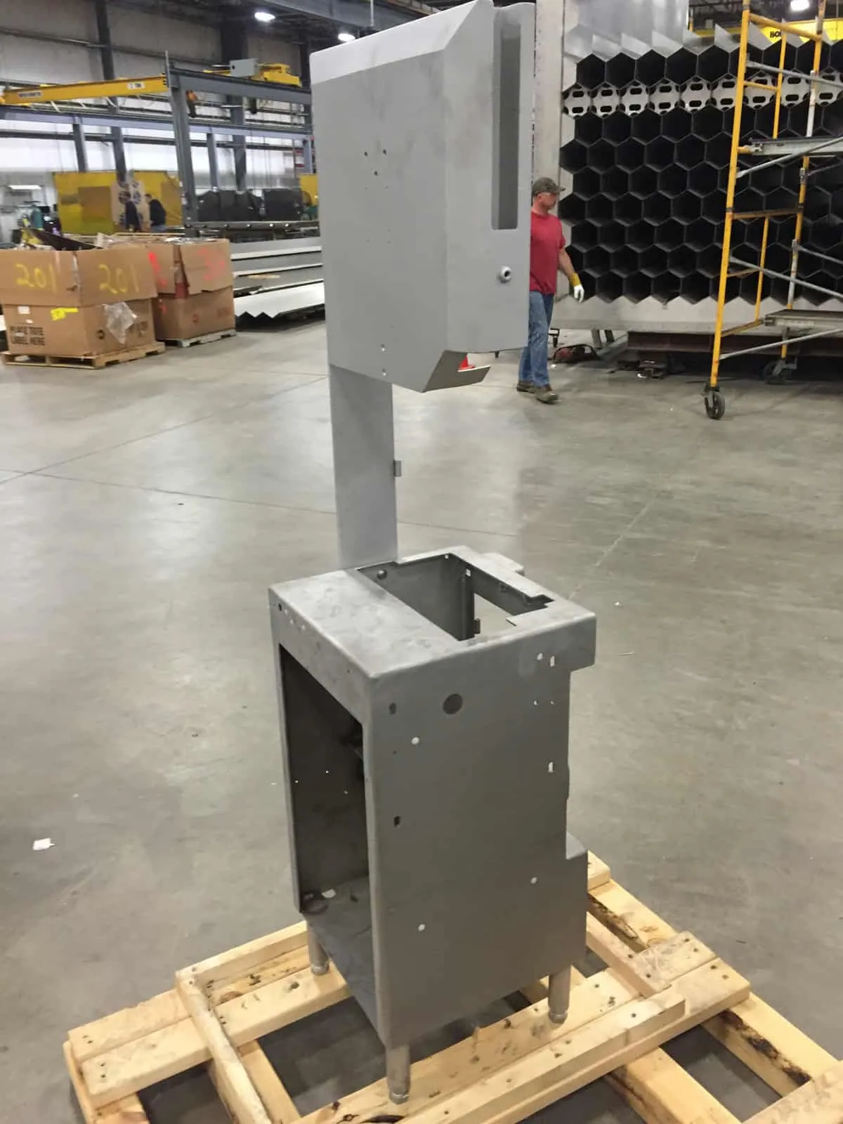Formed 316L stainless steel equipment housing staged on a pallet in the fabrication bay