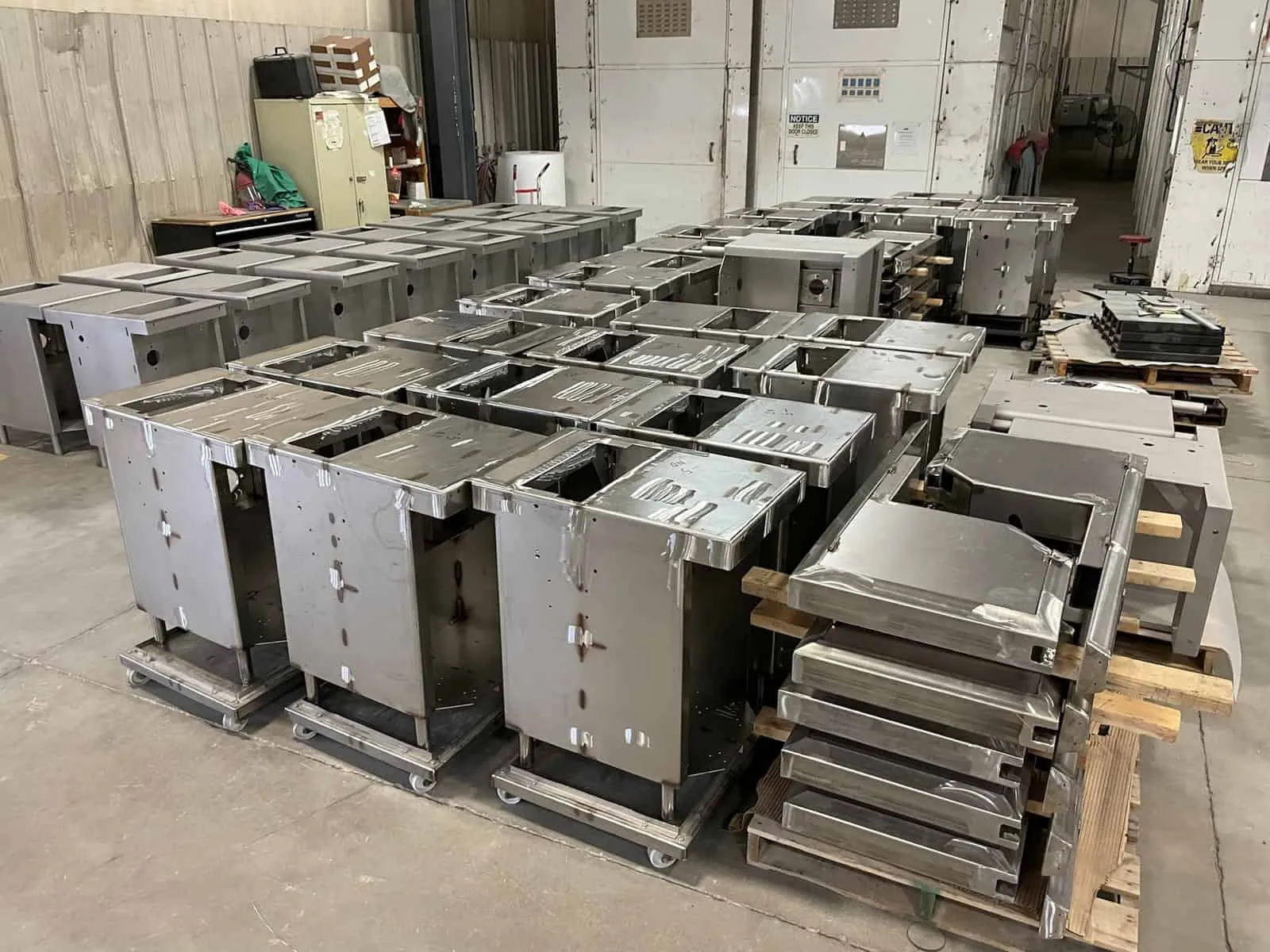 Production run of stainless steel food-service equipment enclosures staged on carts